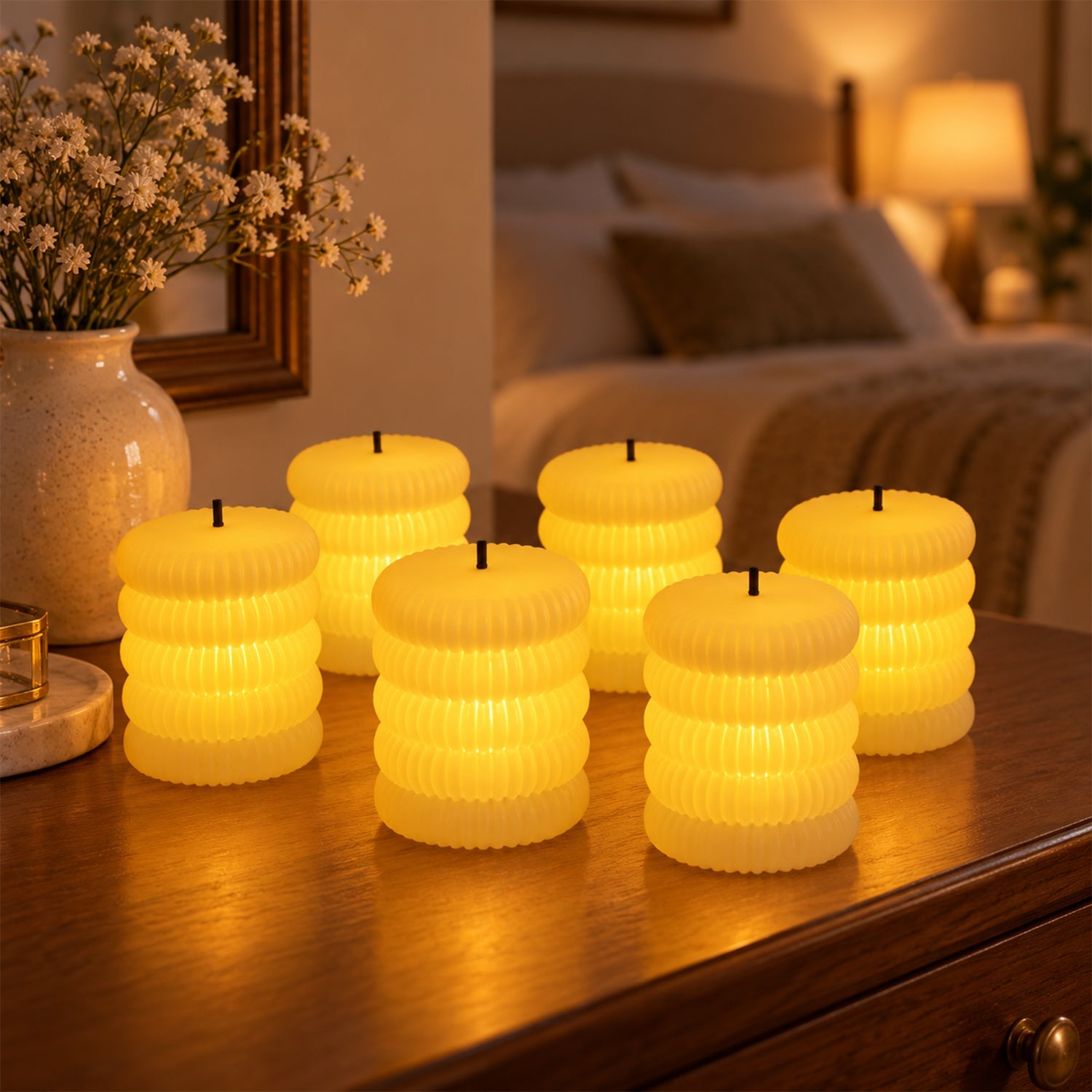 Six glowing ribbed flameless LED tealight candles on a wooden dresser in a bedroom setting.