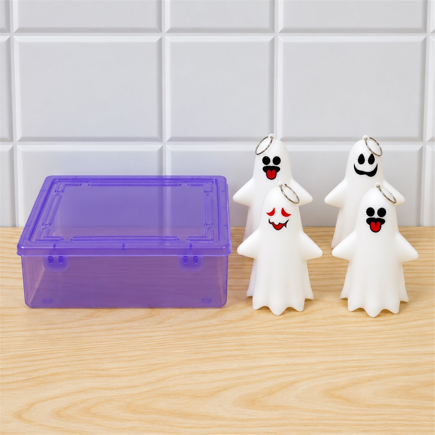 Four white ghost figures with varied faces and a purple transparent storage box are on a wooden surface.