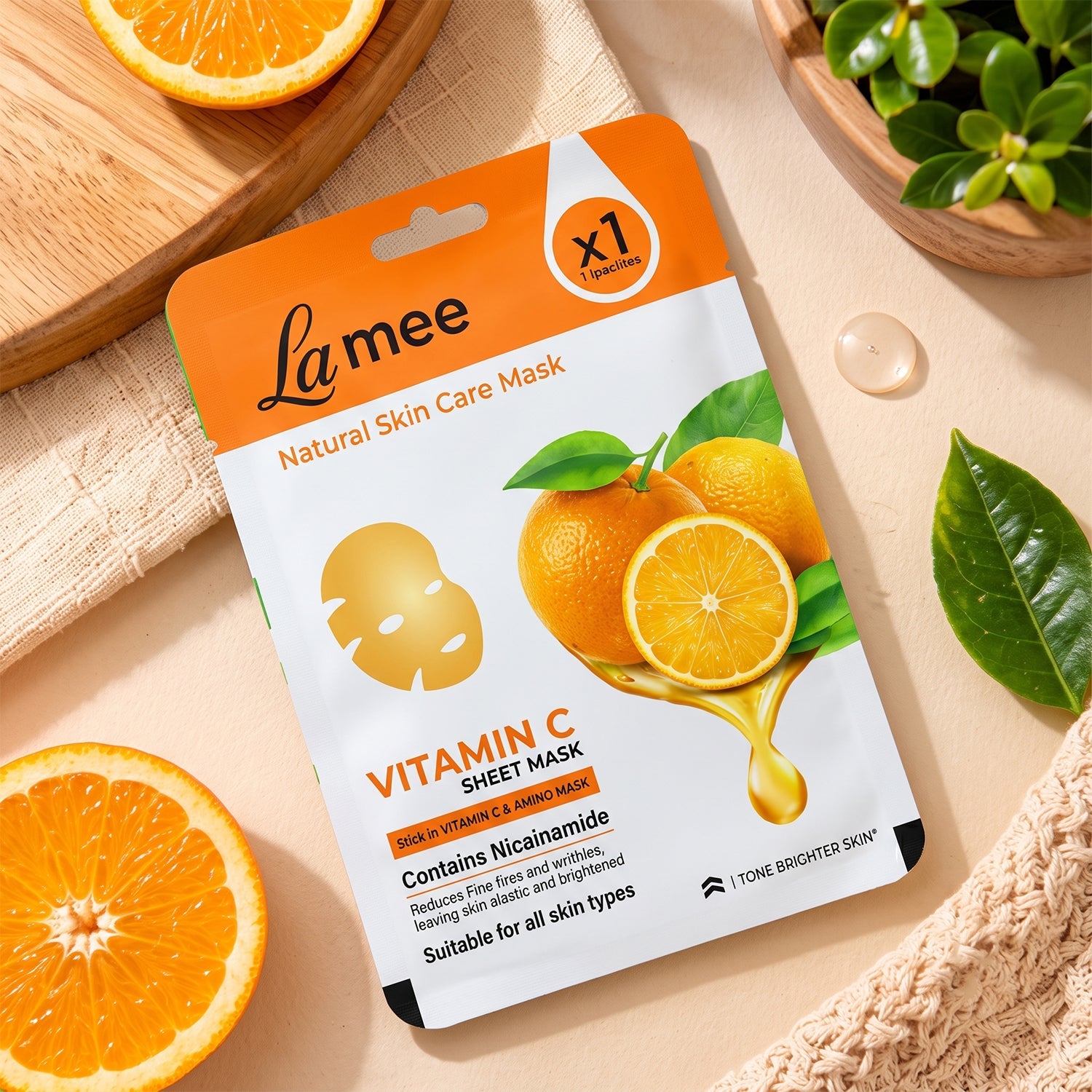 An overhead view of the white and orange sheet mask package, surrounded by orange halves and a beige knitted cloth.