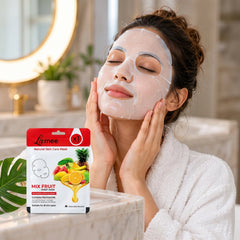 A woman in a white robe wears a sheet mask on her face while touching her cheeks, with a mask package nearby.