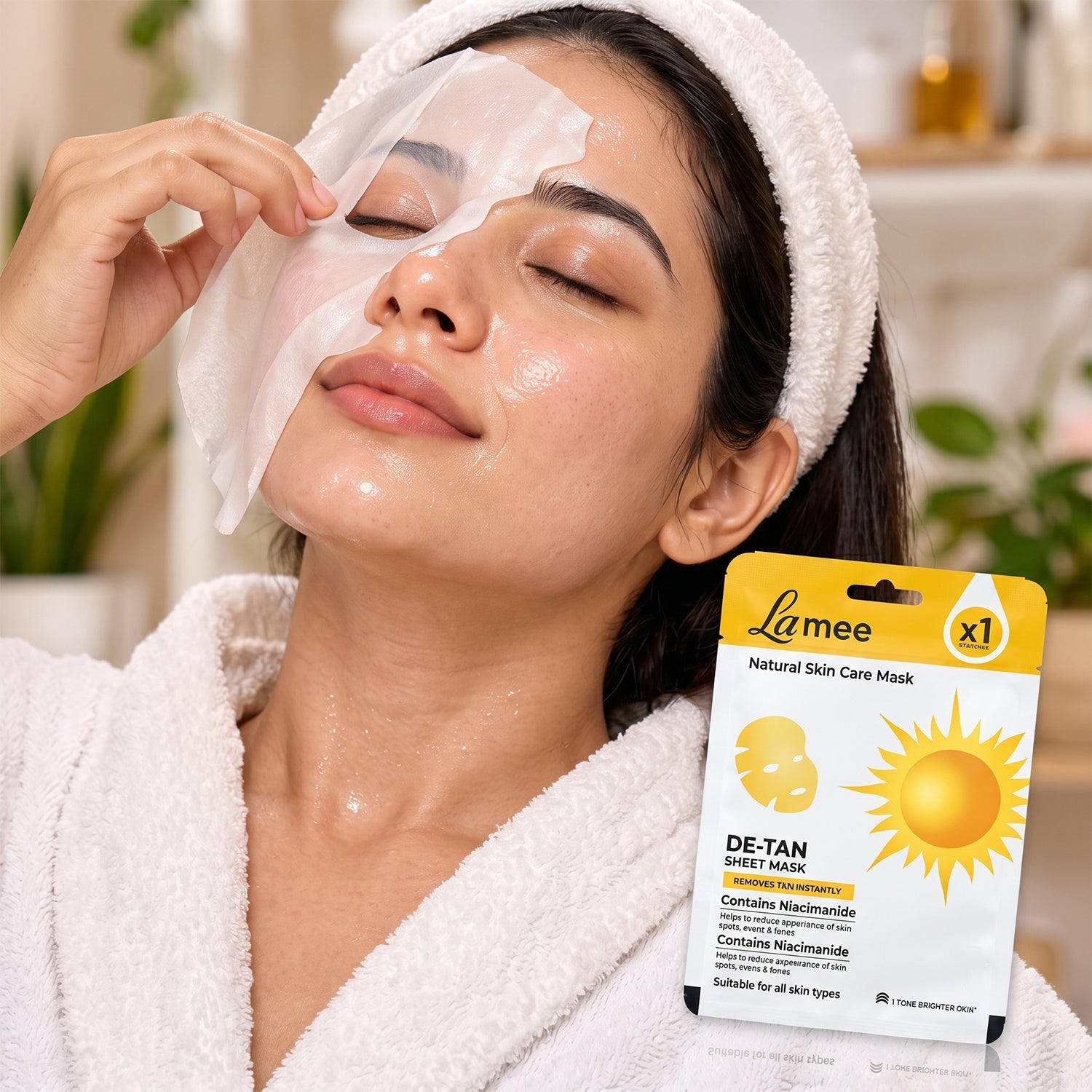 Woman in a white robe removing a white sheet mask from her face, with the product packaging in the foreground.