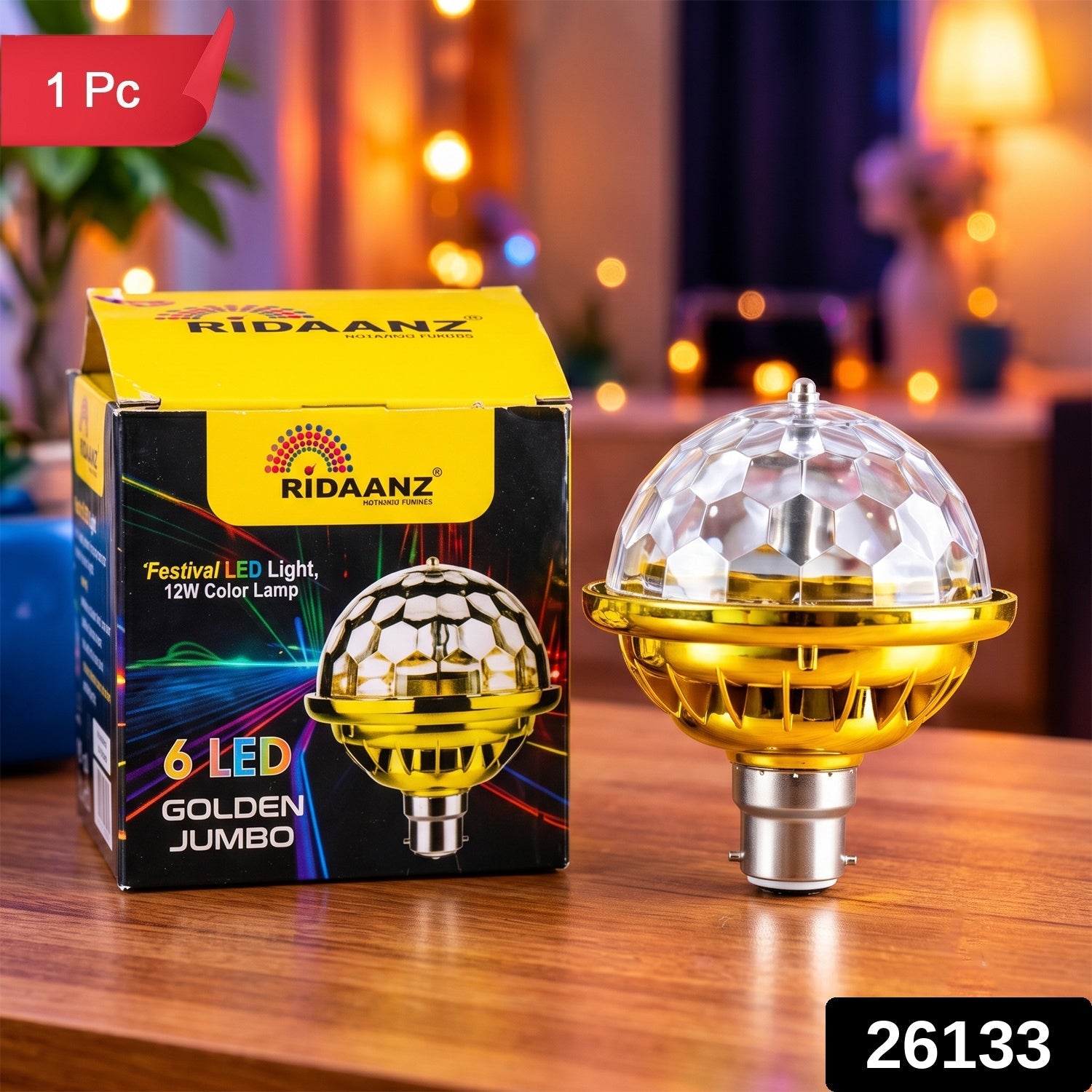 A gold and clear disco bulb with a B22 base sits next to its yellow and black packaging on a wooden table, with text