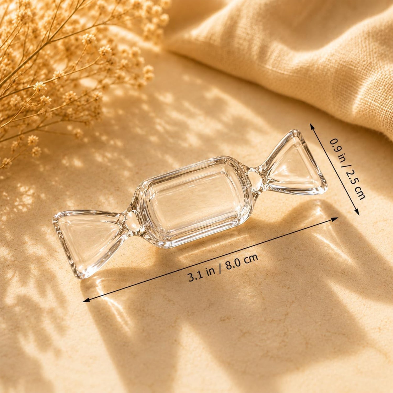 A single clear candy-shaped box is shown with its length and width dimensions marked, resting on a textured beige surface.