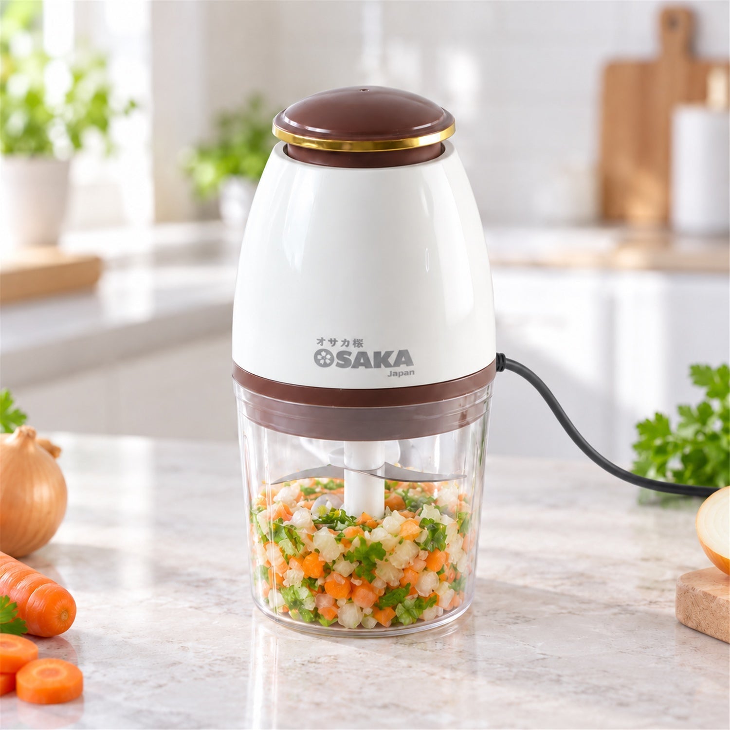 A white and clear electric chopper sits on a kitchen counter, filled with a mix of finely diced green and orange vegetables.