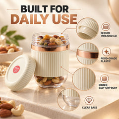 A single cream and clear ribbed container with a rose gold band, open, filled with nuts and dried fruit, showing product