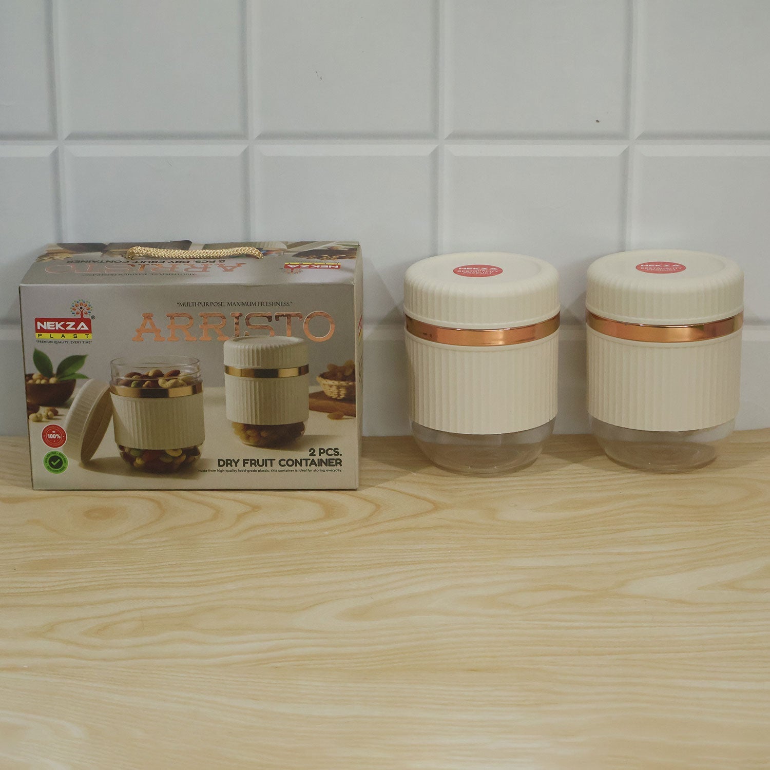 Two cream and clear ribbed containers with a rose gold band next to their product box on a light wooden surface.