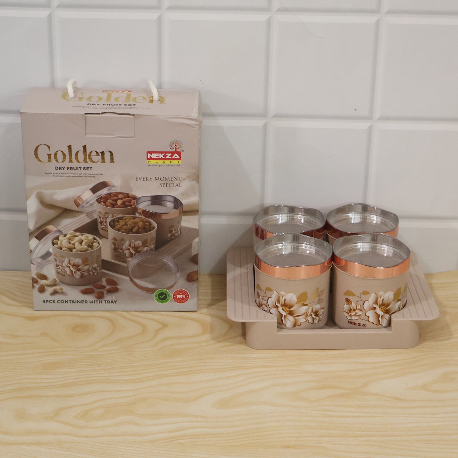The product box and the four-piece floral container set on its tray, displayed on a light wooden surface against white tiles.
