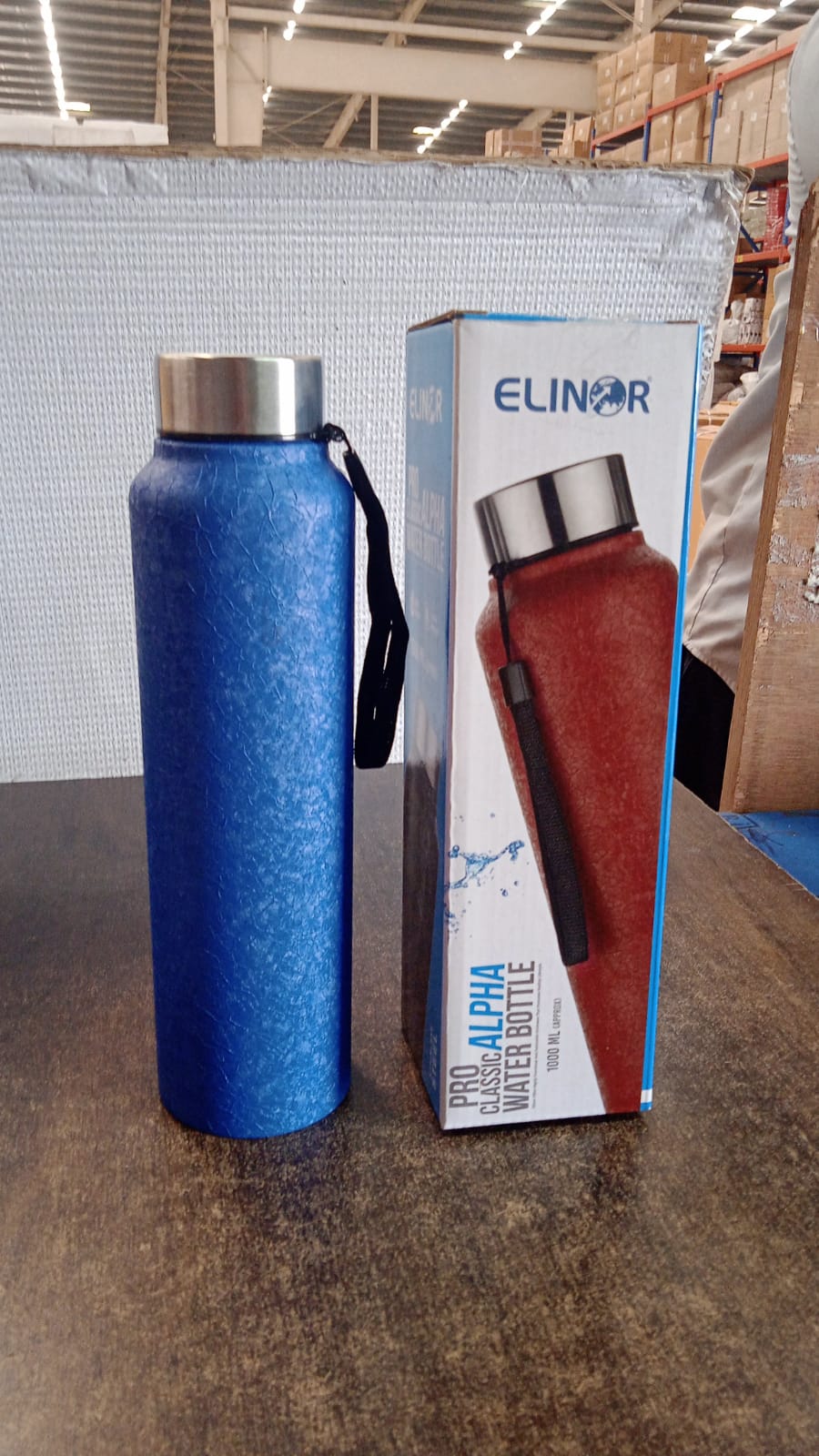 Person holding black stainless steel water bottle with green cap outdoors
