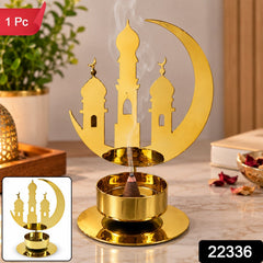A golden metal incense holder with a crescent moon and mosque design, with a brown incense cone burning.