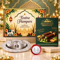 A festive gift box, pistachio wafer rolls, a silver kumkum dish, and a Lakshmi-Ganesh coin on a marble surface with golden