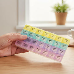Pastel-colored weekly pill organizer with 28 compartments