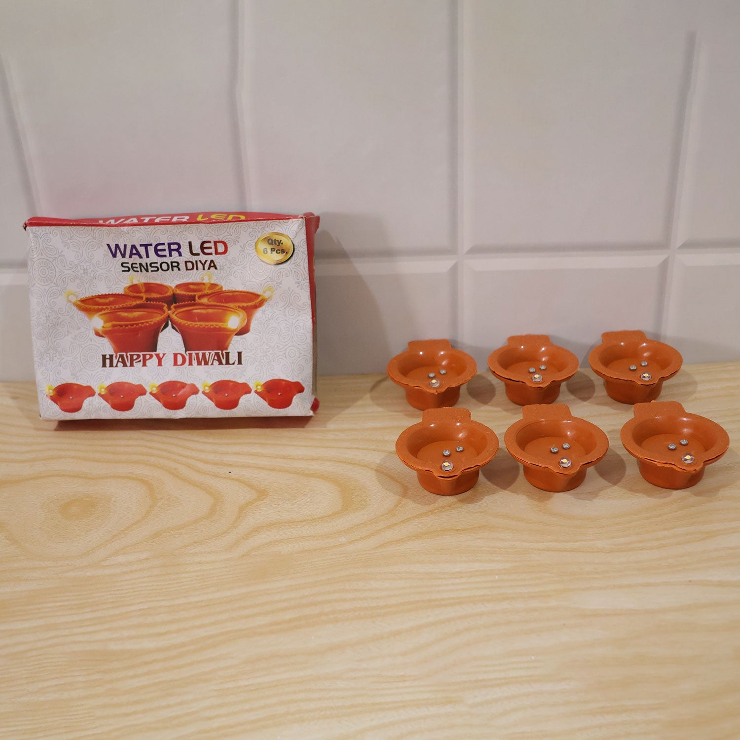 Water-activated LED diyas used in a pooja setting with flowers
