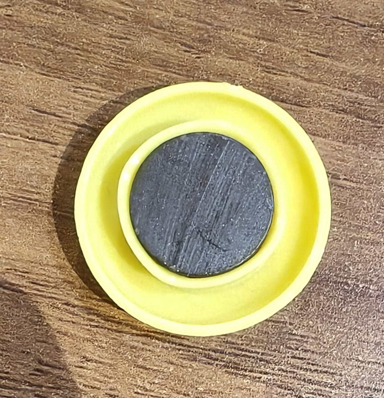 Yellow circular magnet shown with a pen for scale