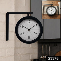 A black double-sided wall clock is mounted on a white brick wall in a kitchen, with a smaller inset image showing the clock
