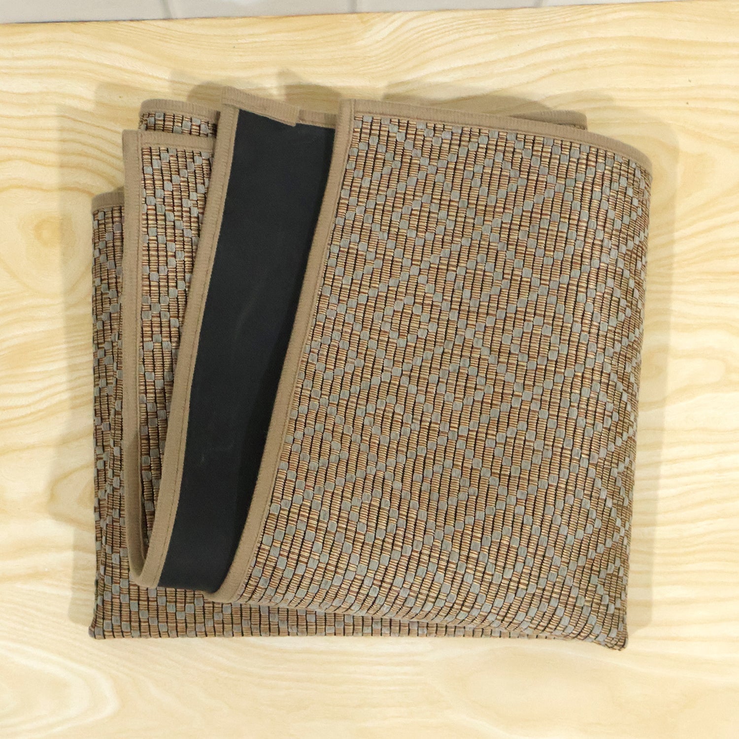 The brown diamond-patterned runner mat is folded neatly, revealing its black backing and woven texture.