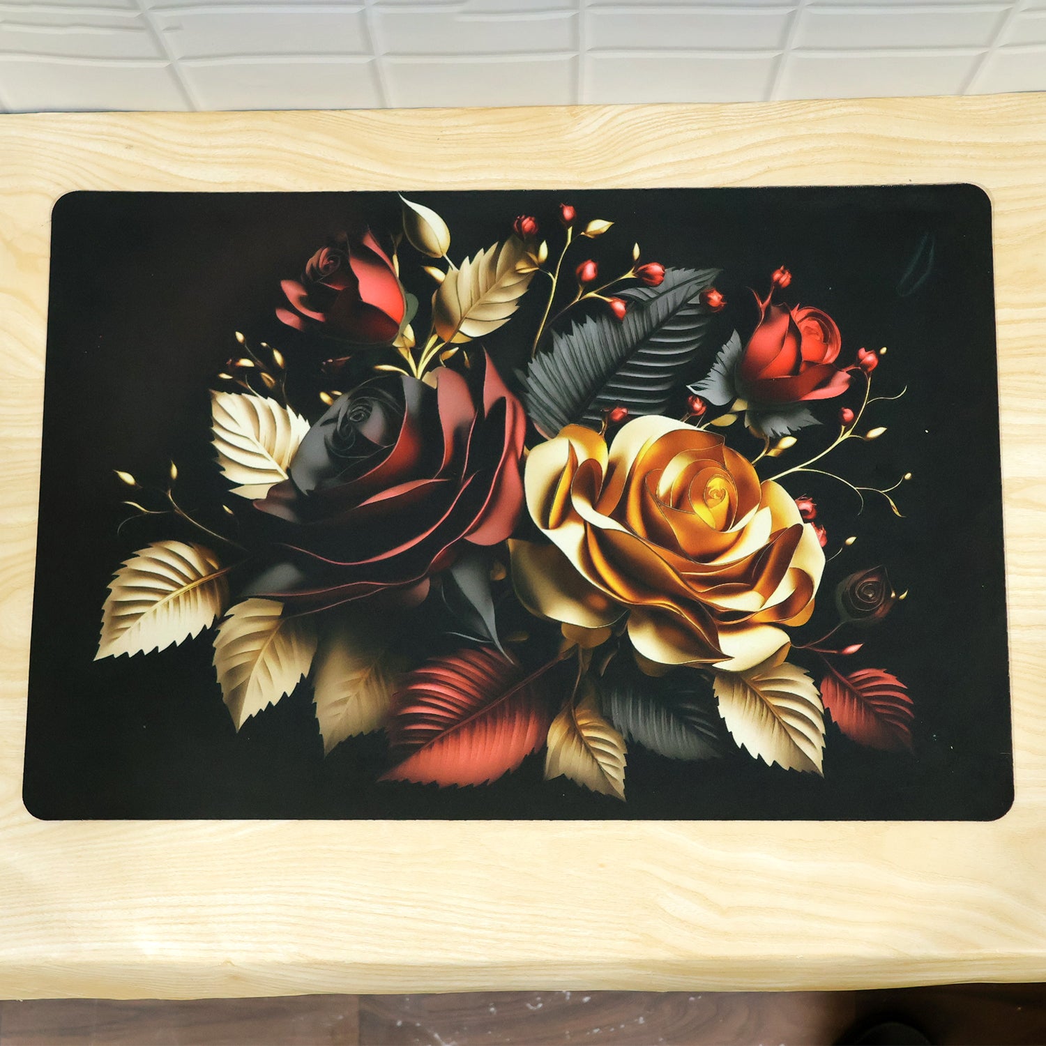 A rectangular black bath mat with an elaborate red and gold rose motif rests on a light wooden surface.