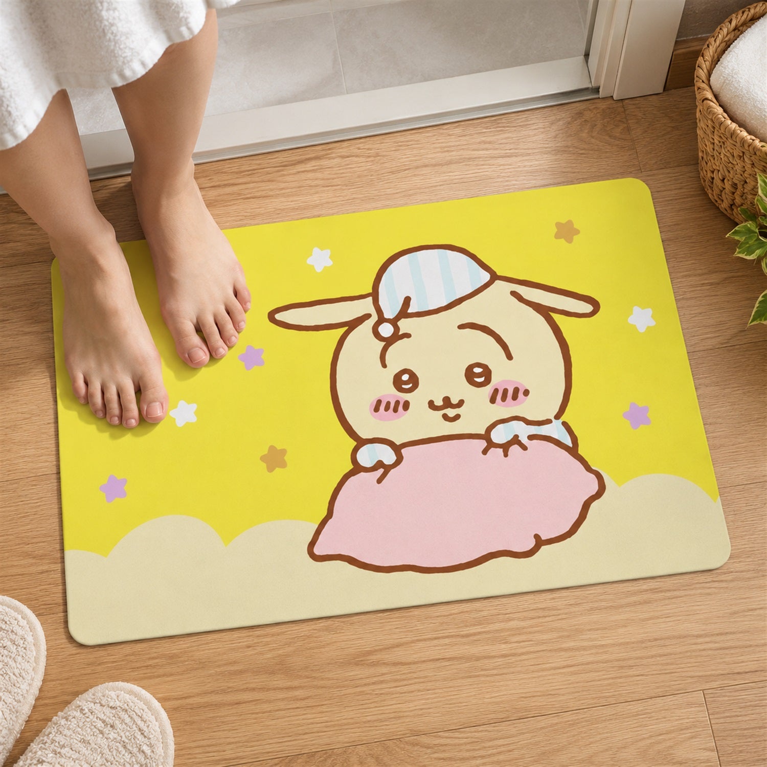 Two bare feet are placed on a yellow bath mat featuring a cartoon bunny snuggled under a pink blanket.
