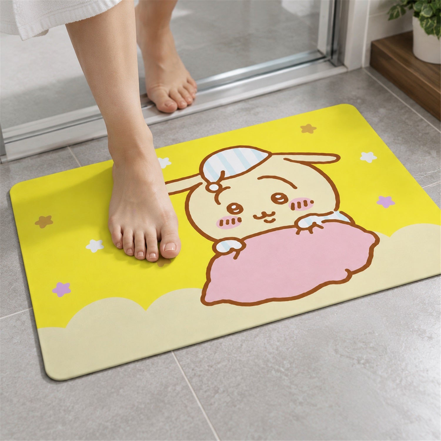 A person's bare feet are positioned on the yellow bath mat, which has a cartoon bunny illustration.
