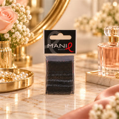 A pack of black bobby pins rests on a polished marble surface, surrounded by elegant vanity items.