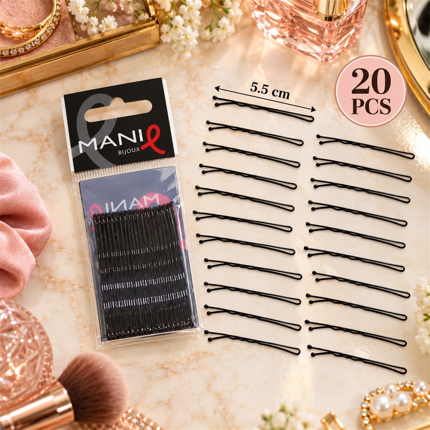 A package of black bobby pins lies on a marble surface next to loose pins and vanity accessories.