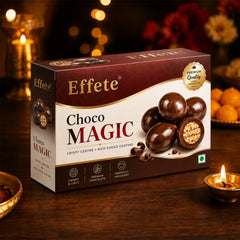 A box of Effete Choco Magic chocolates on a dark wooden table with lit candles and blurred festive decorations in the