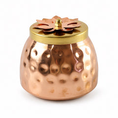 A hammered copper jar with a gold lid and a copper flower knob is centered on a white background, showcasing its textured