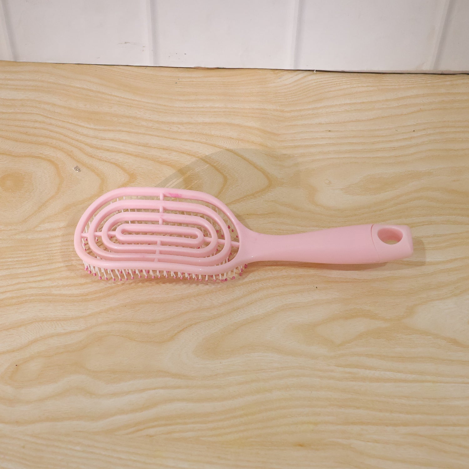 Woman brushing her hair with the pink curved styling brush