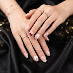 Close-up of a hand with glitter 3D floral press-on nail tips, highlighting the intricate petal and crystal details.
