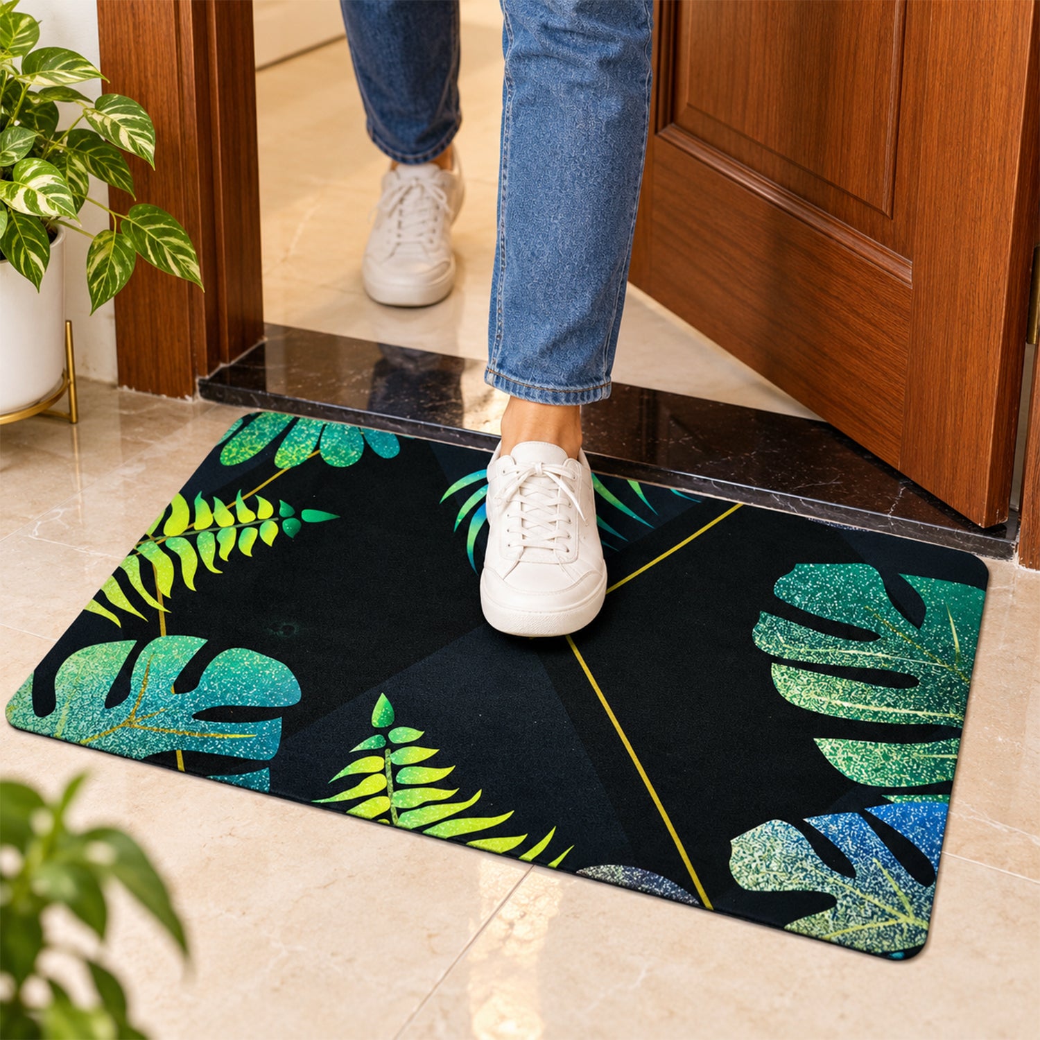 A person in jeans and white sneakers steps onto a black mat with green and blue tropical leaf patterns.