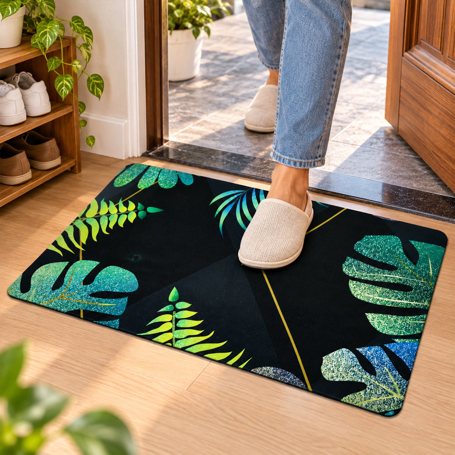 A person wearing light-colored slippers steps onto a black mat adorned with green and blue leaves.