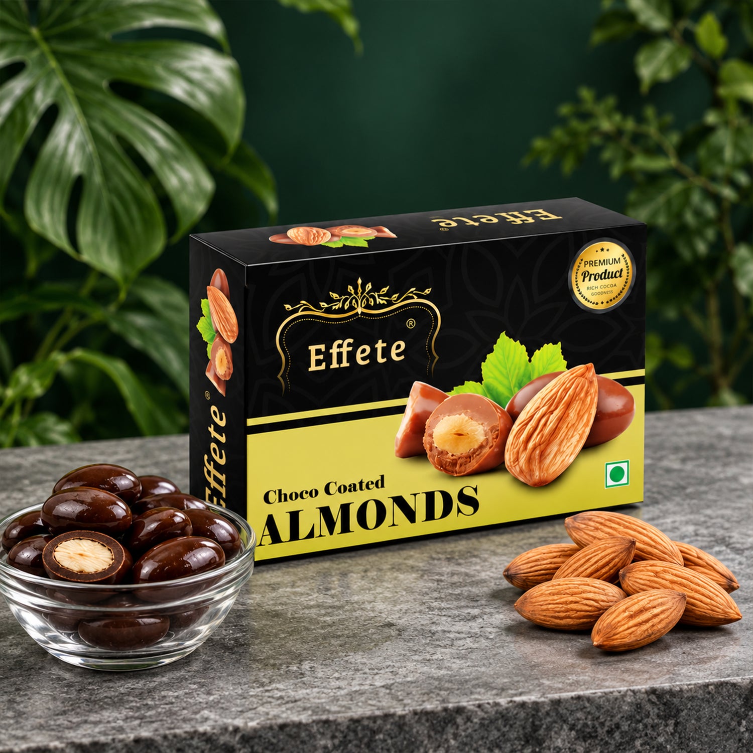 A black and yellow box of Effete Choco Coated Almonds sits on a dark gray table with loose almonds and a bowl of chocolate