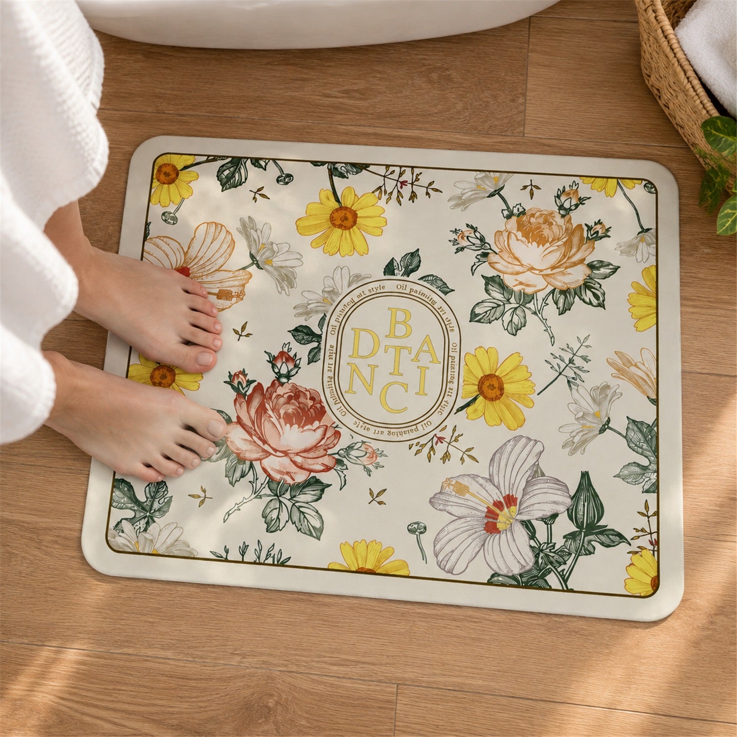 A person's bare feet, partially covered by a white robe, stand on a rectangular floral bath mat with a cream background and