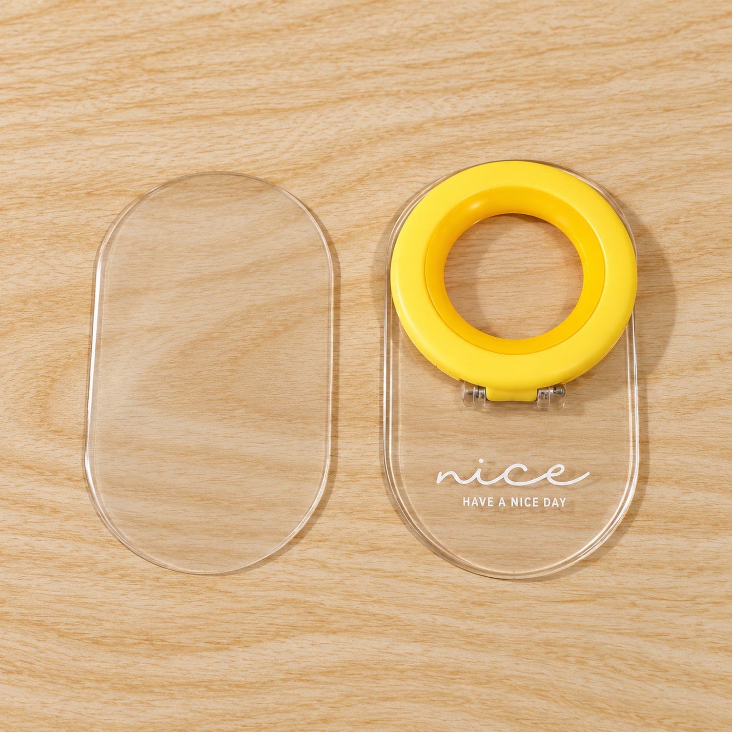 The clear adhesive base and the yellow ring lifter are displayed separately on a light wooden surface.