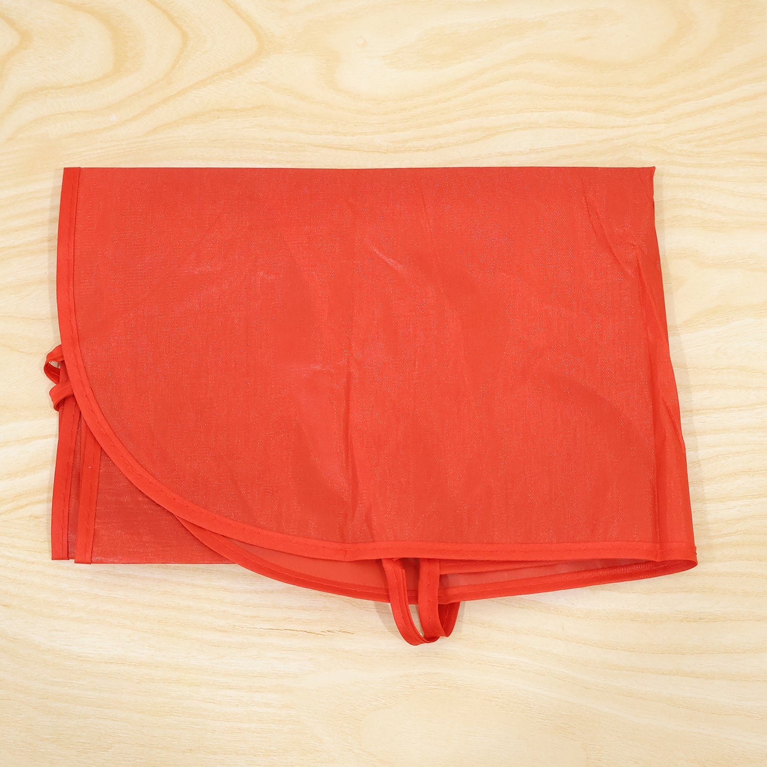 A red Sonifer apron neatly folded into a rectangular shape on a light wooden surface.