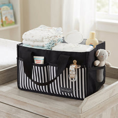 A black and white striped organizer bag caddy, filled with baby essentials, sits on a light wooden changing table.