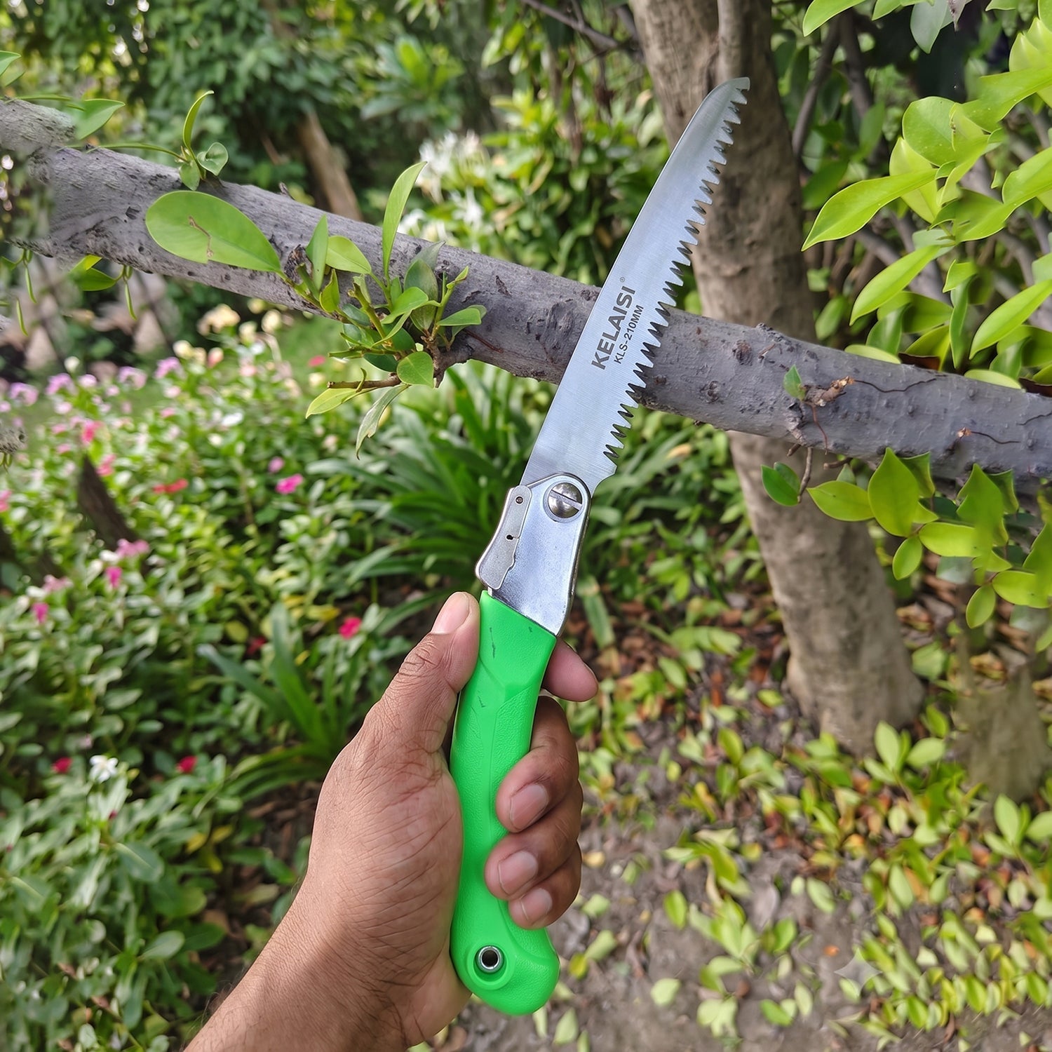 Folding saw in action cutting wood, with non-slip handle visible