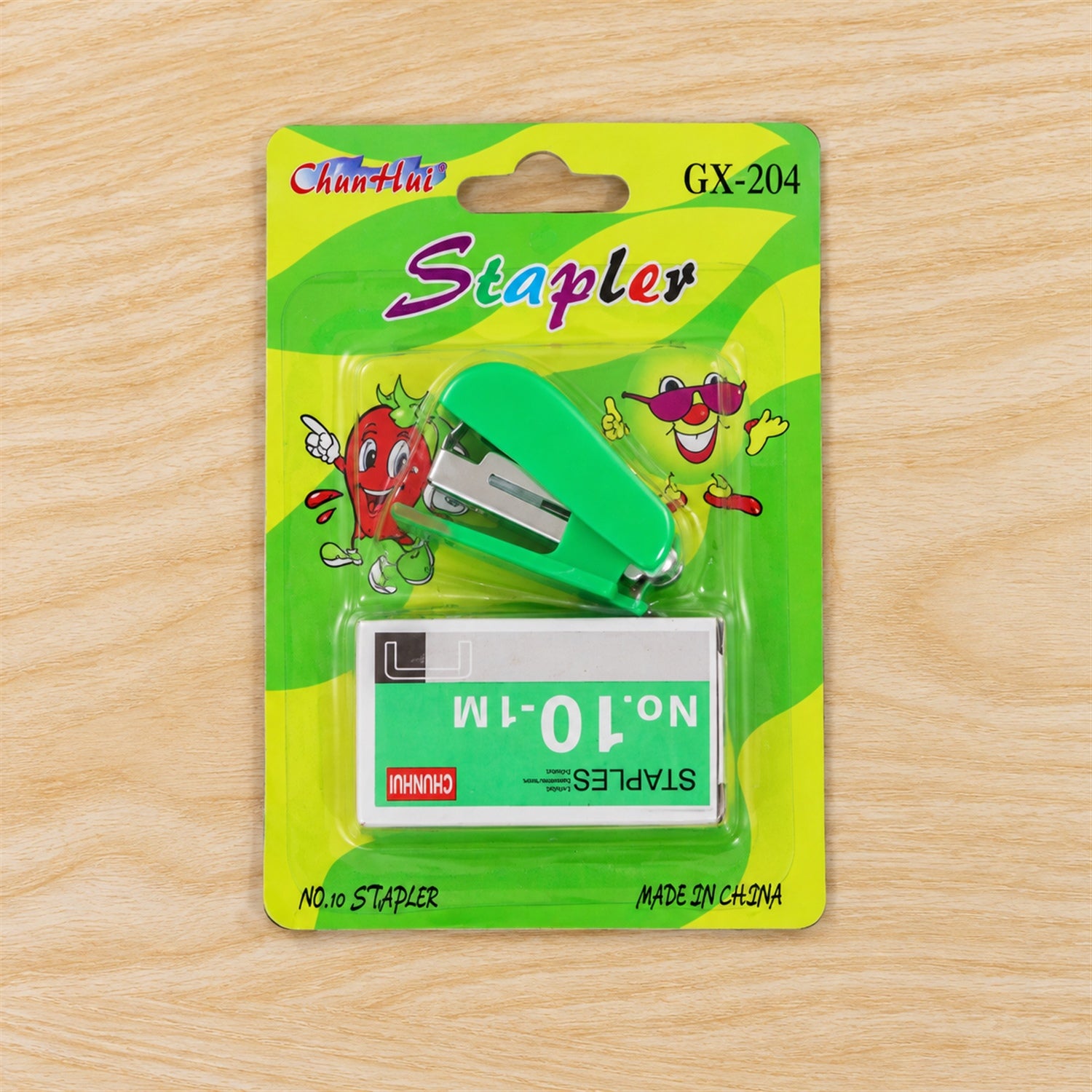 A green mini stapler and a box of staples are sealed in clear plastic packaging with colorful cartoon graphics.
