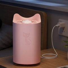 A pink cat-shaped mosquito killer lamp with an embossed cat design is plugged into a wall outlet on a wooden nightstand next
