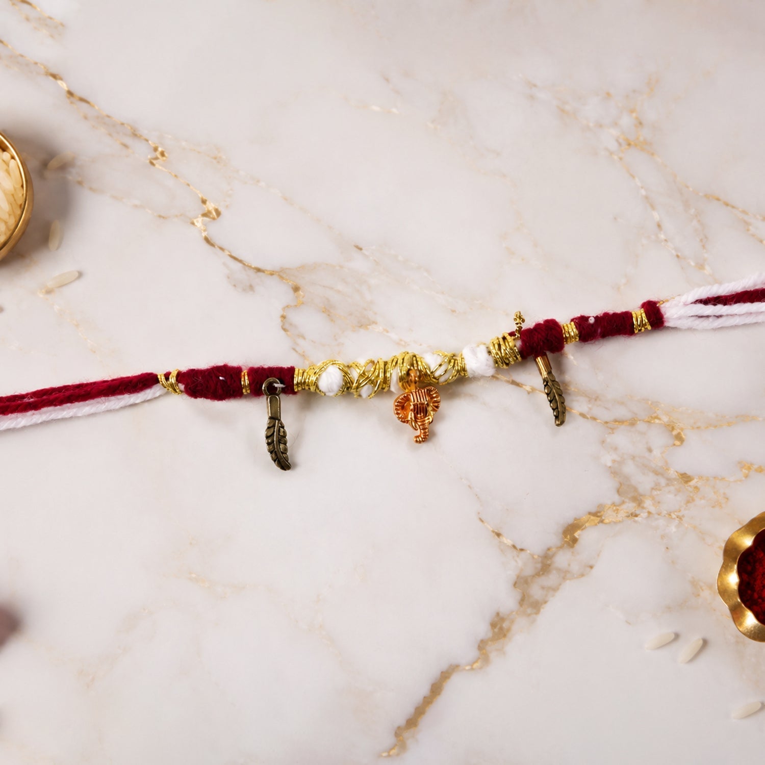 Close-up of Ganesh & Feather Charm on Thread Rakhi