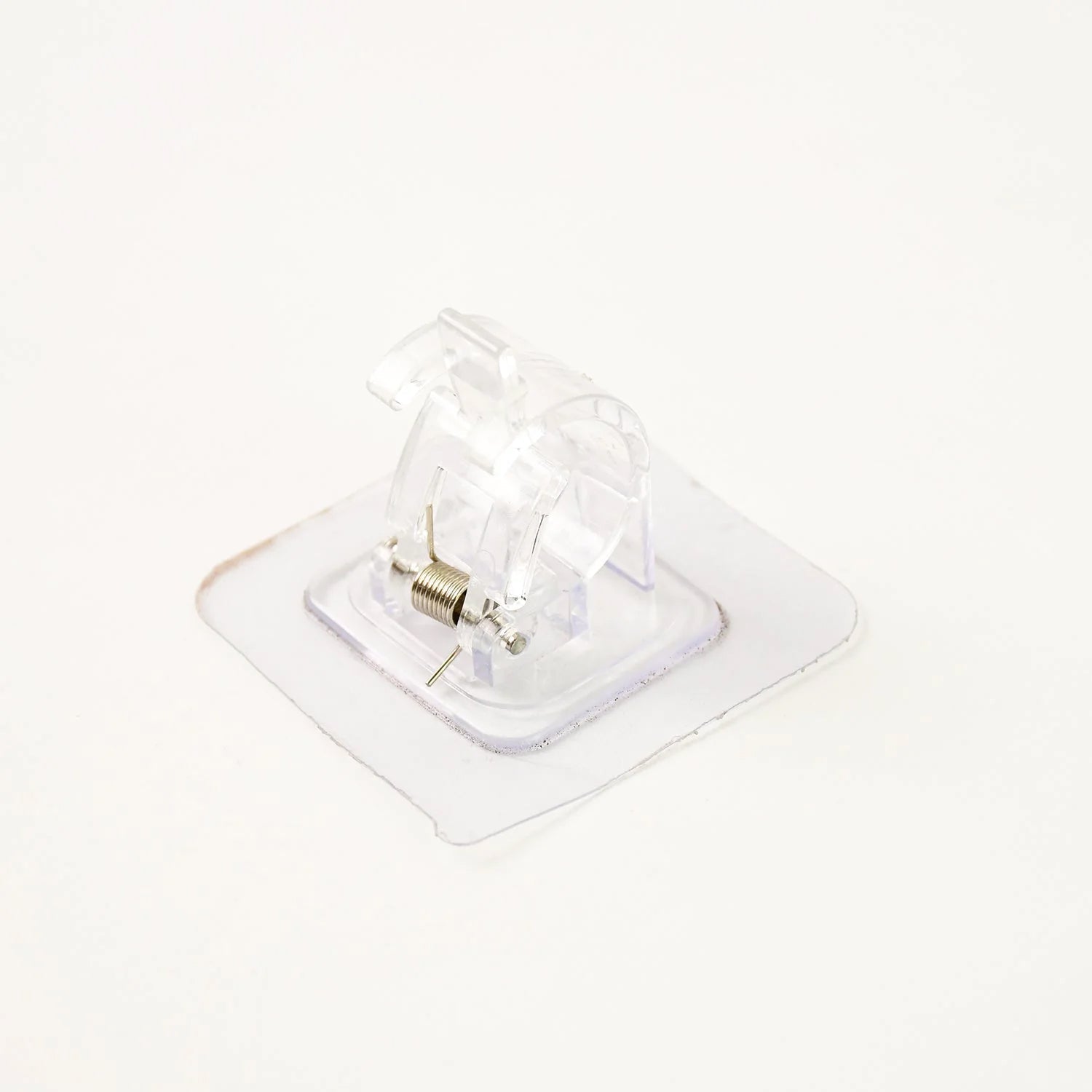 Clear self-adhesive curtain rail clip installed on wall