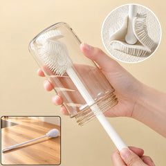 A hand holds a clear glass bottle being cleaned by a white silicone brush, with a close-up of the brush head.