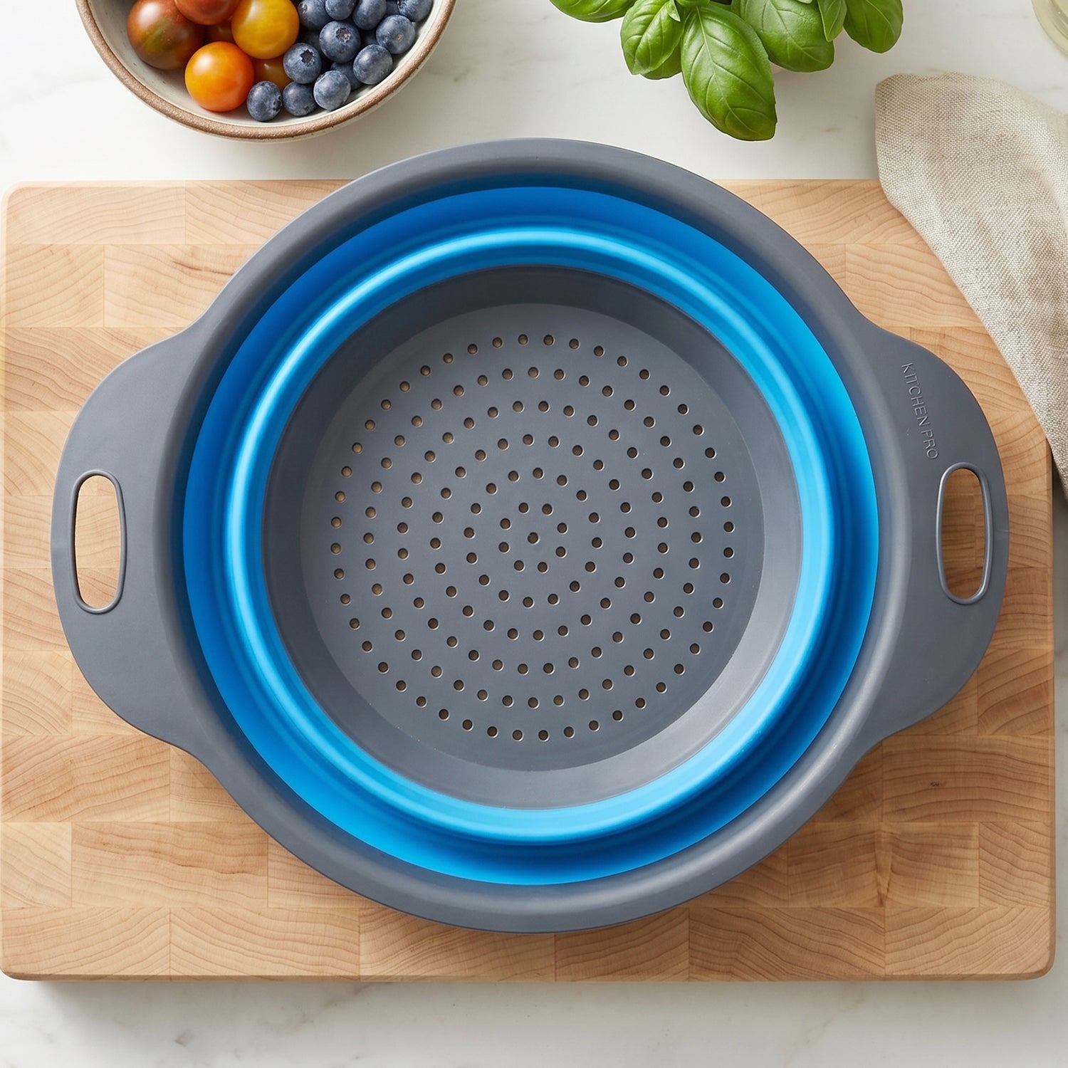 Space-saving silicone colander with side handles for washing fruits and draining pasta.