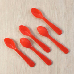 Set of five white plastic spoons fanned out on a surface