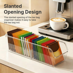 Clear plastic organizer with a slanted opening, holding many colorful tea bags next to a coffee machine with a latte.
