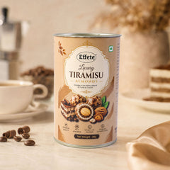 A tall, cylindrical tin of Effete Luxury Tiramisu Almonds sits on a white counter with coffee items.
