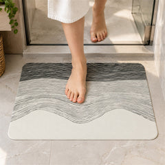 A person steps out of a shower onto a rectangular mat with a black and white wavy line design.