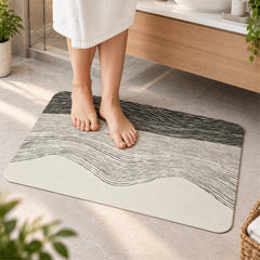 A person stands on a rectangular mat with a black and white wavy design in a modern bathroom setting.