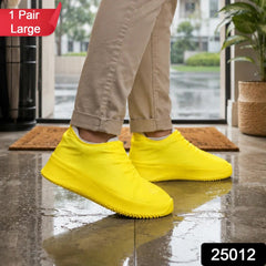 A person wearing khaki pants and bright yellow silicone shoe covers stands on a wet tiled floor, with a "1 Pair Large" label.