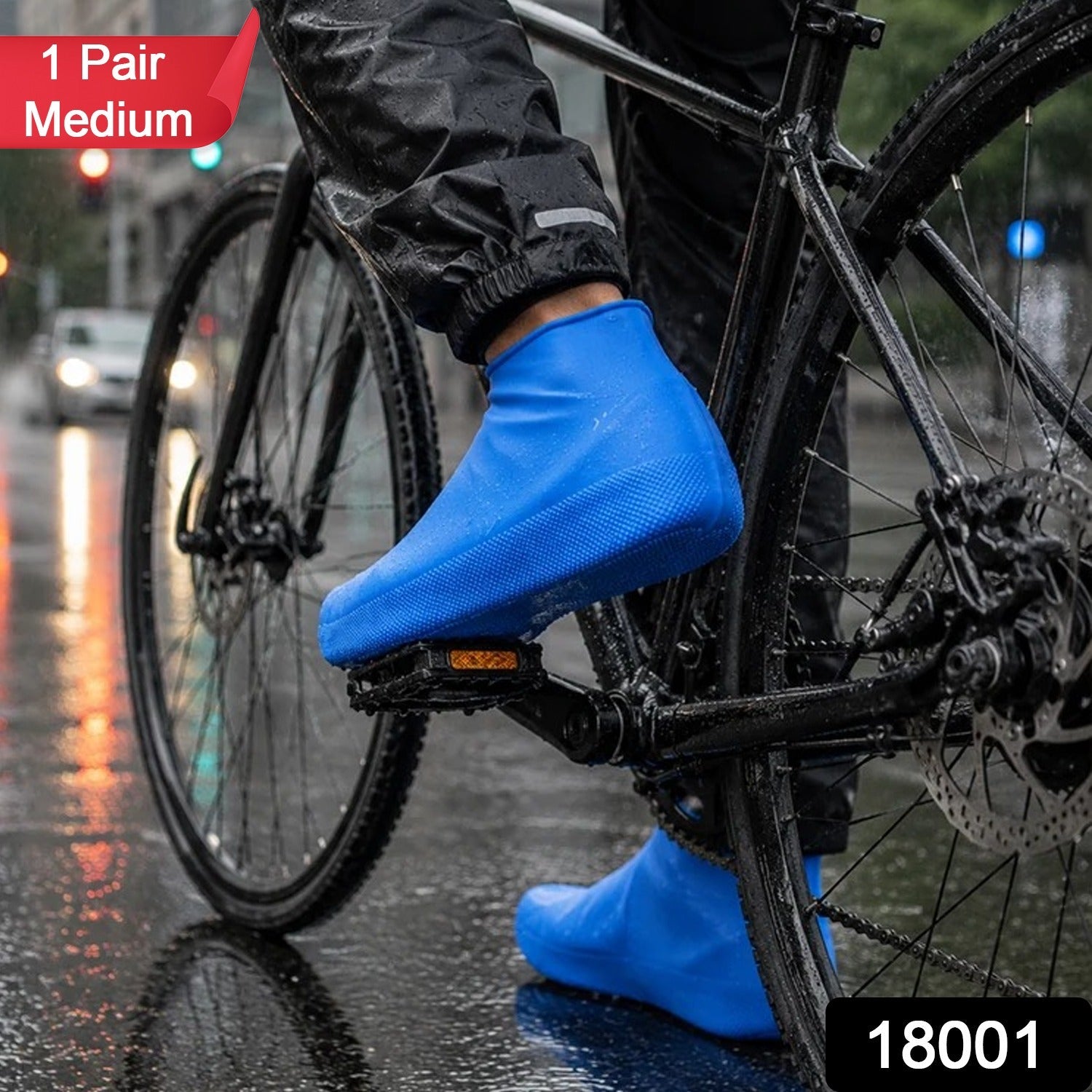 A person on a bicycle wears blue waterproof shoe covers on a wet city street, with a red "1 Pair Medium" label.