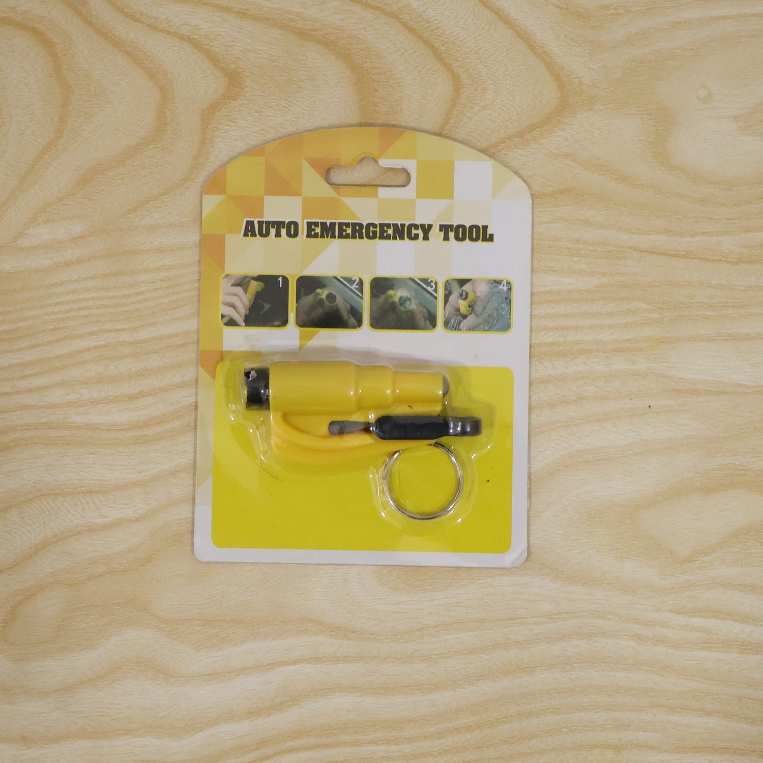 The yellow auto emergency tool, a keychain car safety hammer, is displayed in its retail packaging on a light wooden